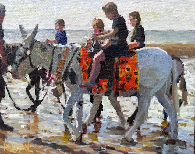 A group of children having a donkey ride with water and reflections on the wet beach