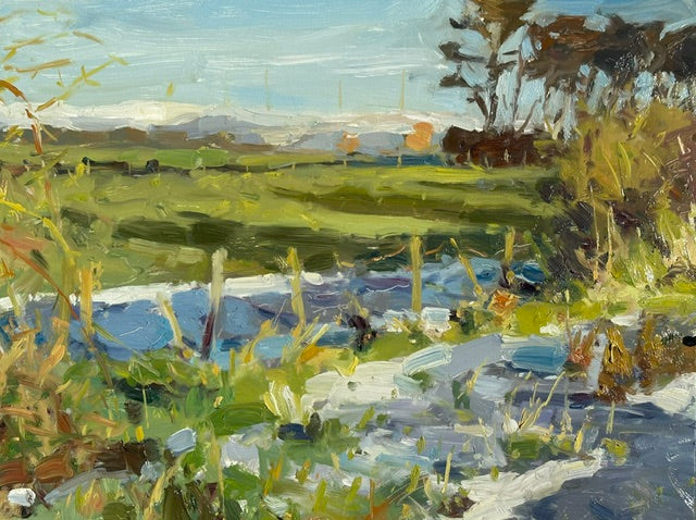 Impressionistic landscape painting featuring a grassy field, a blue icy stream in the foreground, distant hills, and trees under a pale sky, rendered with visible oil paint brushstrokes.