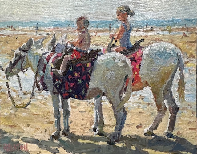 Brother and older sister enjoying a donkey ride on the beach