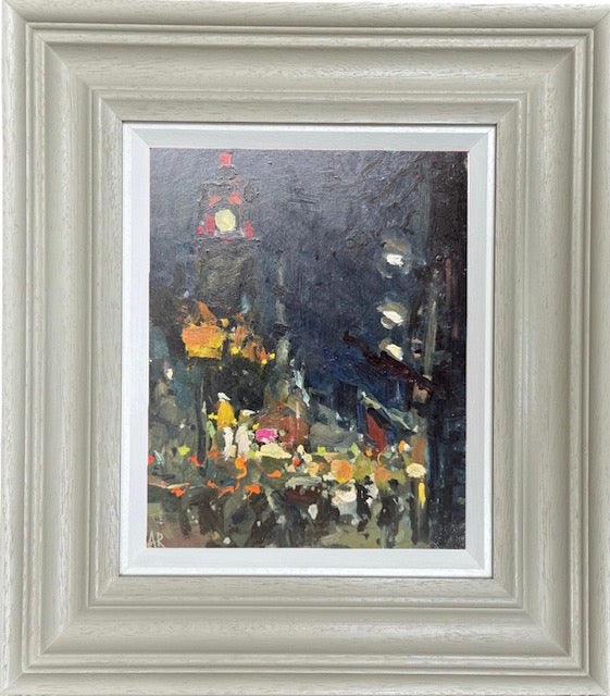 A framed impressionist-style painting of a city street at night, featuring a clock tower and glowing lights, set within a wide distressed light gray frame and white mat.