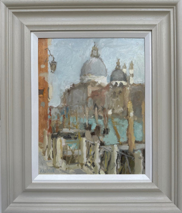 Framed impressionist oil painting of a Venetian canal scene with domed buildings of the salute rendered in muted blue, gray, brown, and beige tones, set in a wide light gray frame.