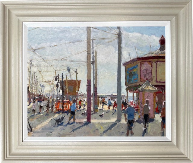 An impressionist-style painting of a seaside street scene with pedestrians, utility poles, and a building, shown in a wide off-white frame with a white mat.