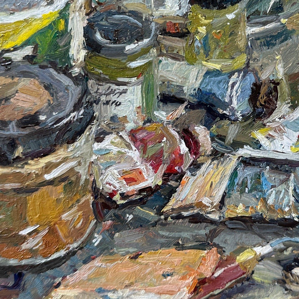 Impressionistic oil painting of a cluttered artist's studio table with paint tubes, brushes, and canvases, rendered in textured impasto brushstrokes of gray, beige, brown, blue, and red.