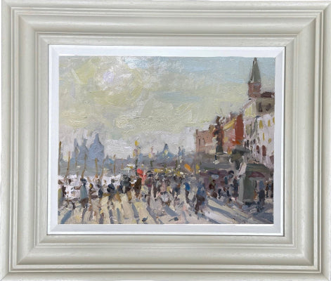 Framed impressionist oil painting of a bustling street scene with figures, buildings, and a church spire, presented in a wide white frame with a white mat.